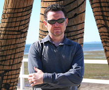 Stevon Newton standing at the timber entry sculpture