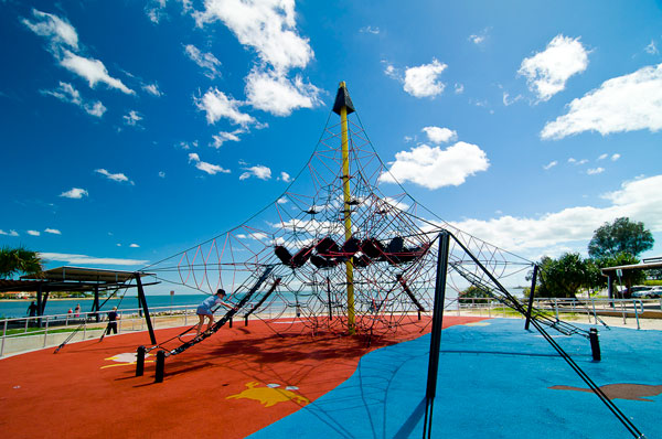 Colourful net playground beside the bay, with blue sky and water in the background.